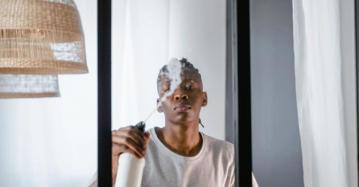 Un jeune homme utilise un pulvérisateur pour nettoyer une fenêtre en verre à l'intérieur d'une pièce moderne.