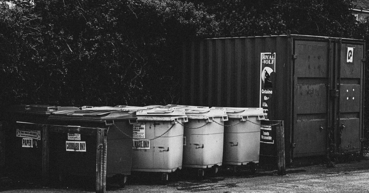 Image monochrome de poubelles et de conteneurs dans un environnement urbain.