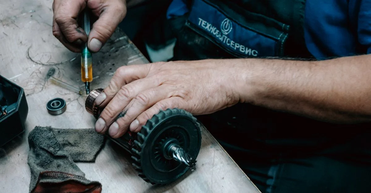 Vue détaillée d'un technicien travaillant sur une pièce d'engrenage mécanique avec des outils de précision sur un établi.