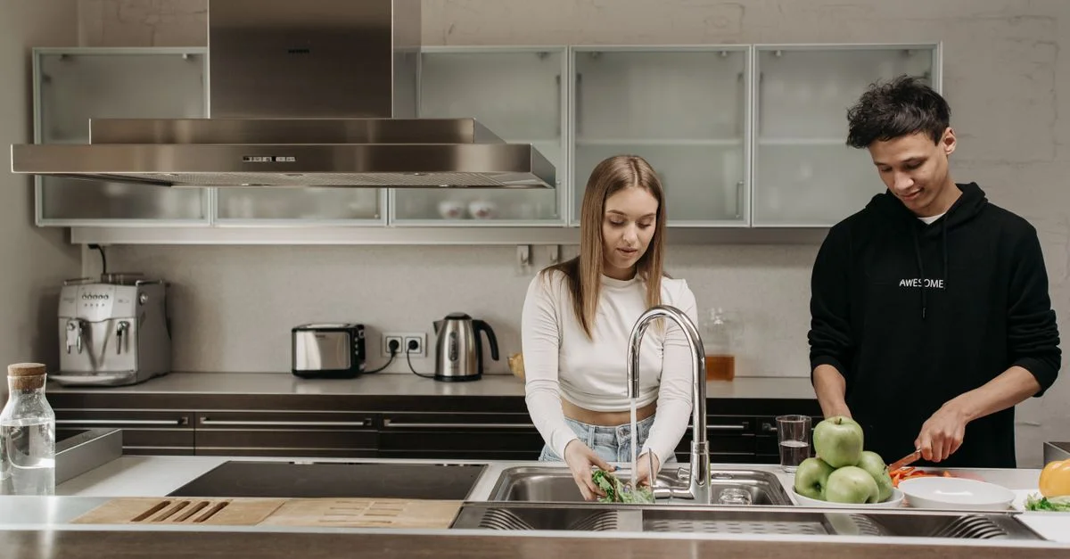 Jeune couple préparant des aliments frais ensemble dans un cadre de cuisine contemporain.