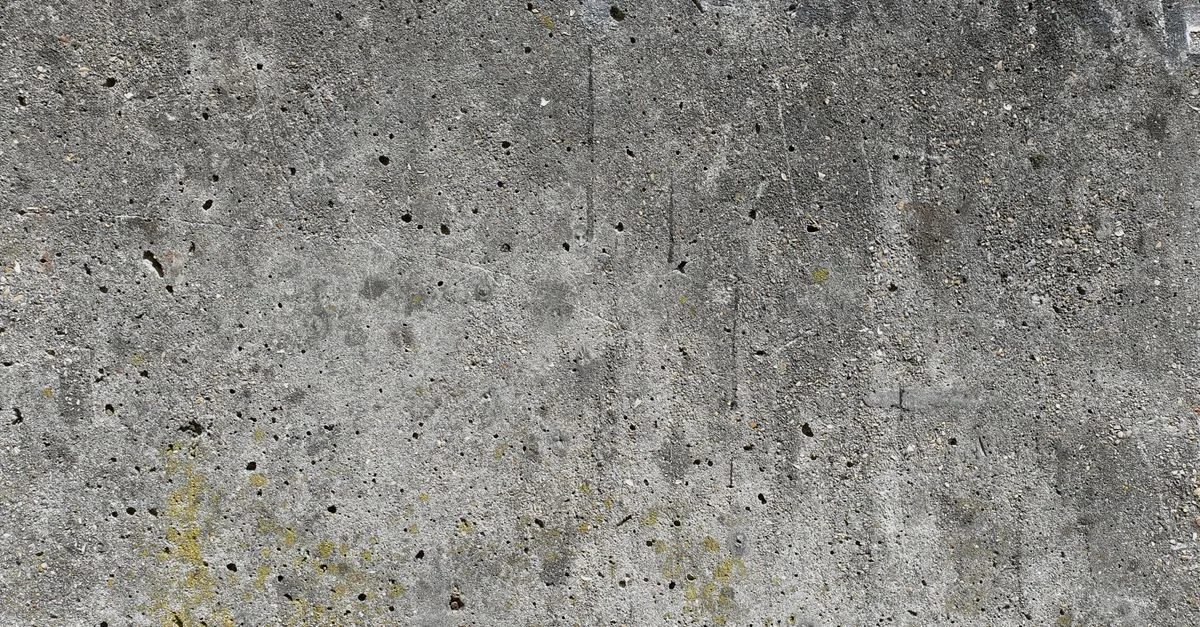 Gros plan d'une surface de mur en béton grunge présentant des taches et des trous.