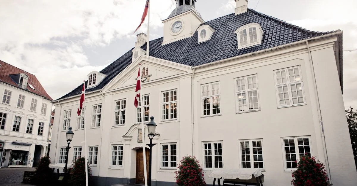 Élégant bâtiment de mairie blanc avec des drapeaux, mettant en valeur l'architecture classique.