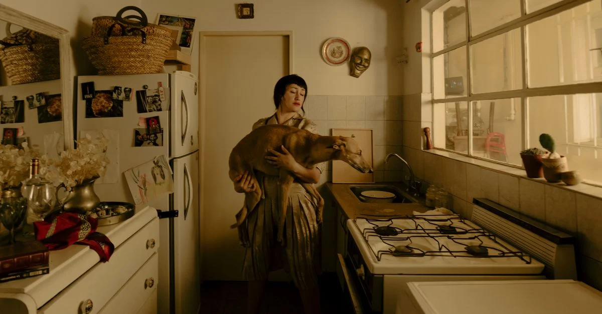 Une femme tient un chien dans une cuisine au style vintage, évoquant une atmosphère nostalgique.