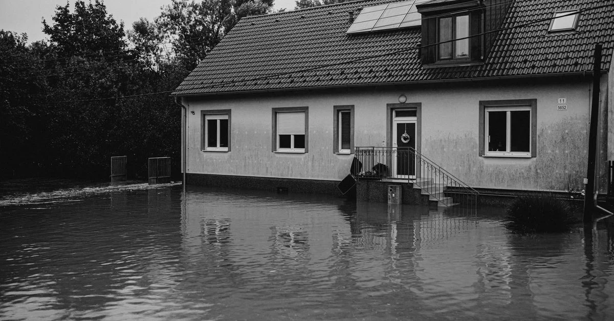 Une image en monochrome d'une maison suburbaine touchée par des eaux d'inondation.