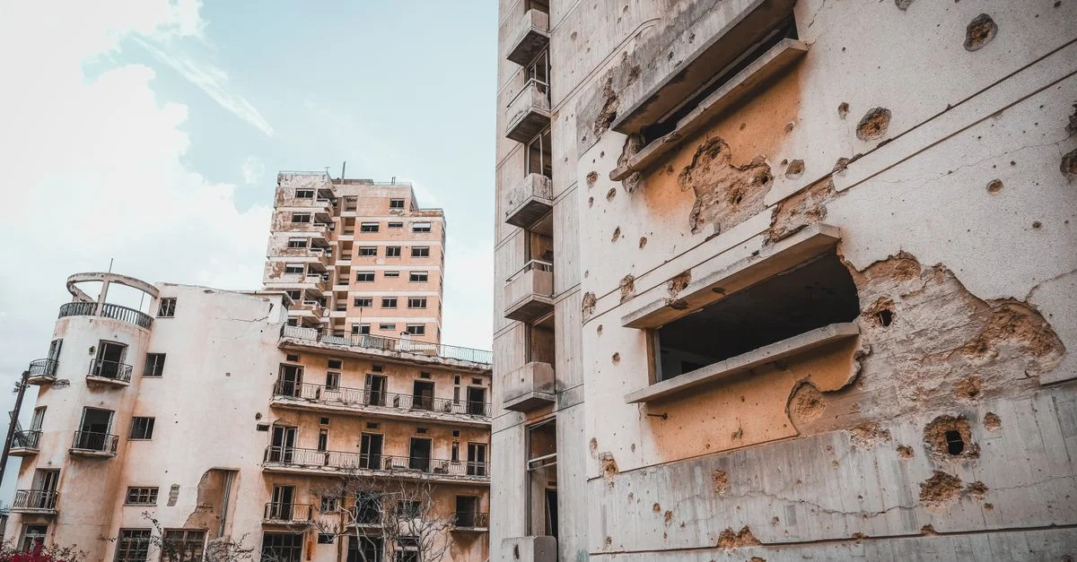 Les bâtiments en béton endommagés à Chypre montrent des signes de guerre et de délabrement, sous un ciel bleu.