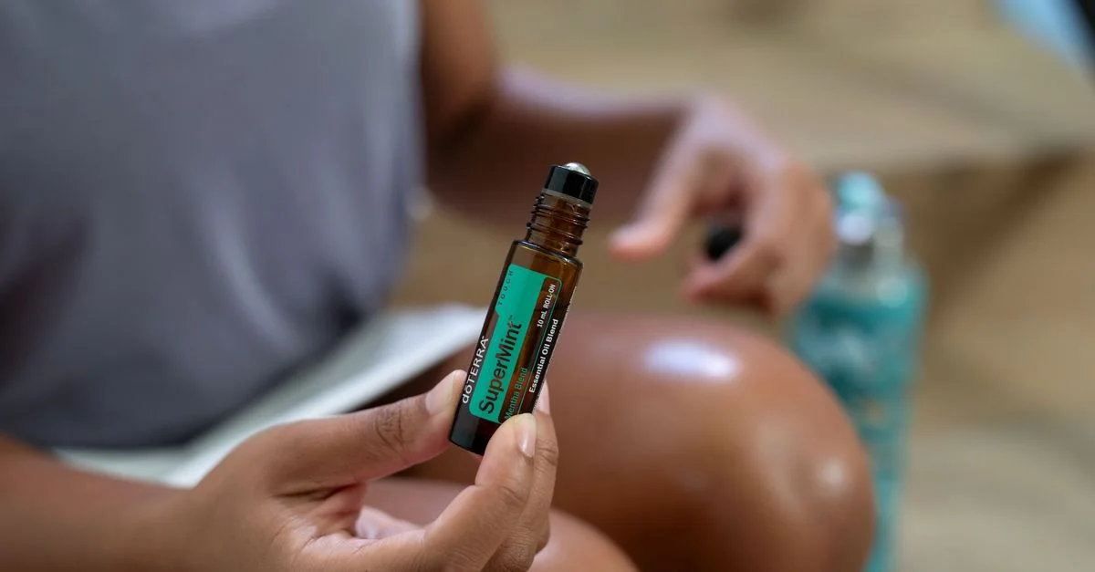Une femme tenant un flacon roll-on d'huile essentielle de menthe super doTERRA en gros plan.