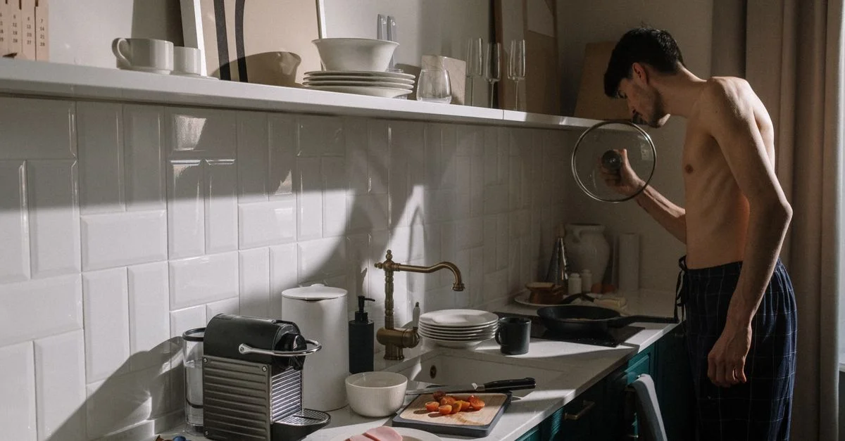 Un jeune homme prépare le petit-déjeuner dans une cuisine chic, illustrant une routine matinale détendue.