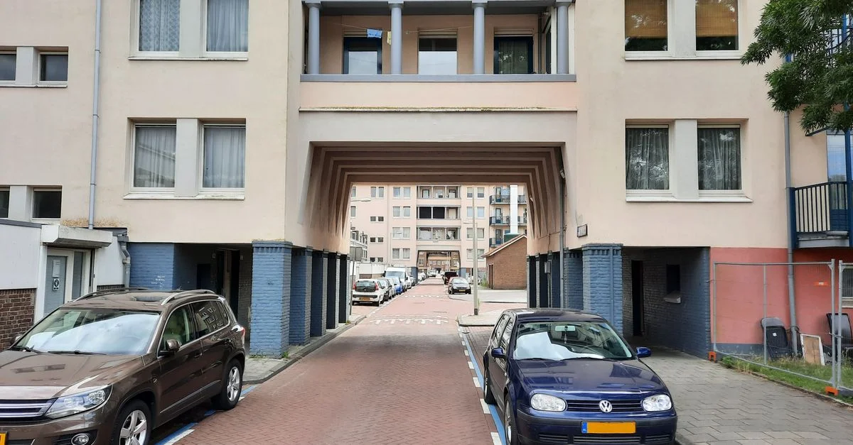 Zone résidentielle urbaine à Amsterdam avec des voitures garées et des immeubles d'appartements.