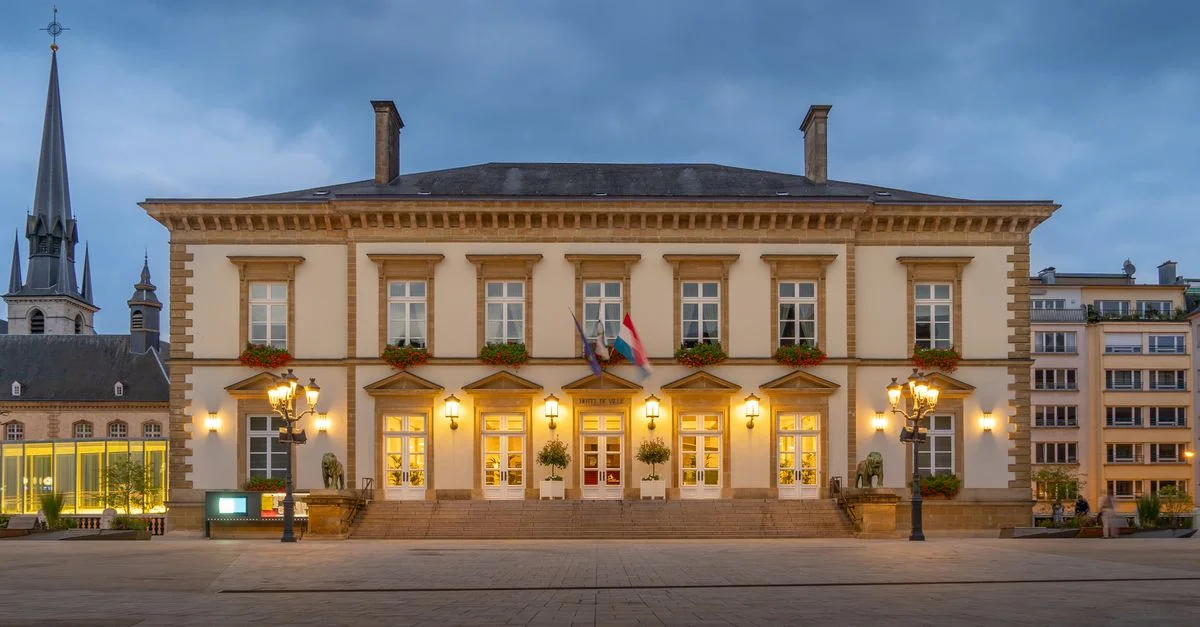 Bâtiment historique illuminé de la ville de Luxembourg pendant l'heure bleue, mettant en valeur l'architecture européenne classique.