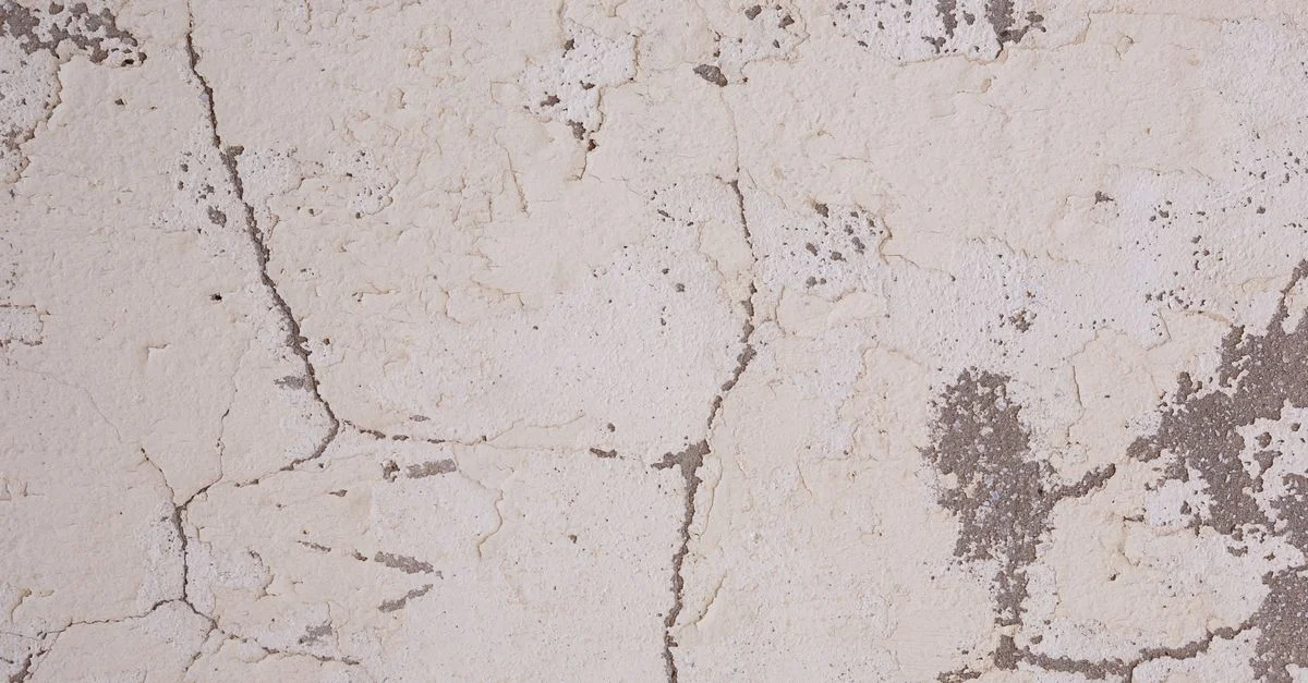 Image haute résolution d'une texture de mur en plâtre fissuré avec des détails de surface rugueuse, idéale pour les arrière-plans et le design.