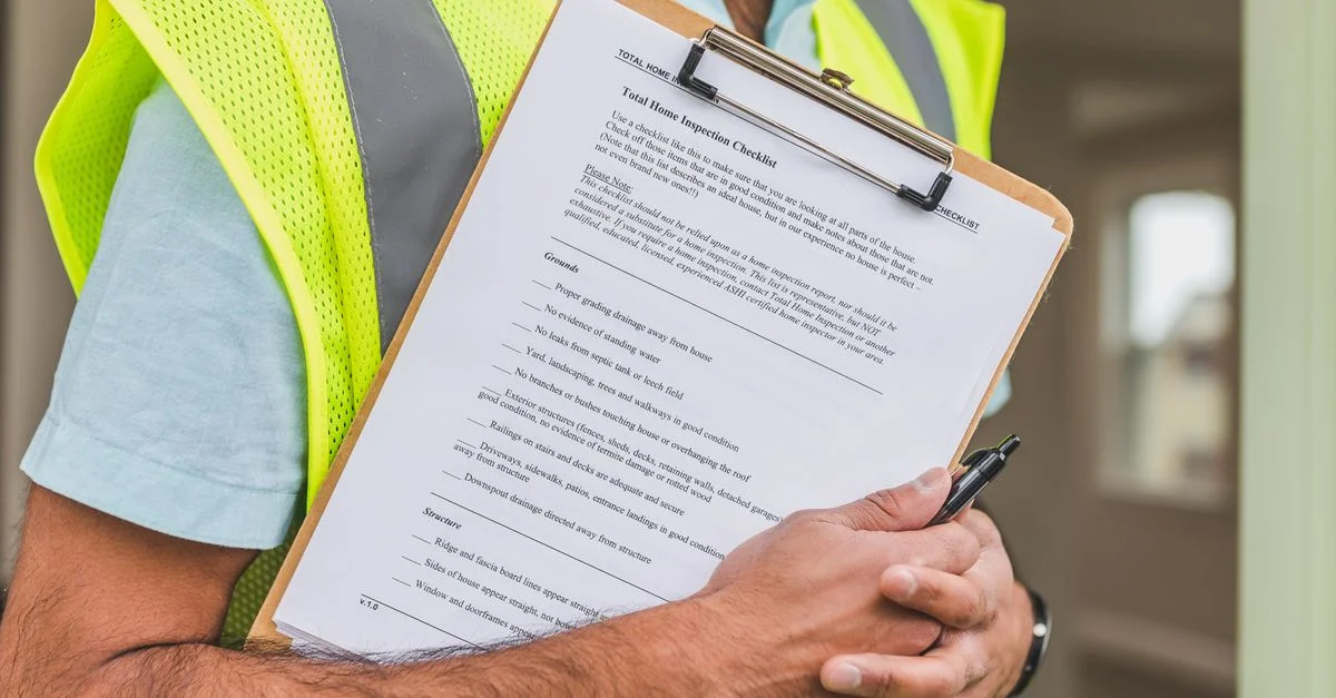 Gros plan d'un inspecteur de maison tenant une liste de contrôle sur un clipboard avec un stylo.