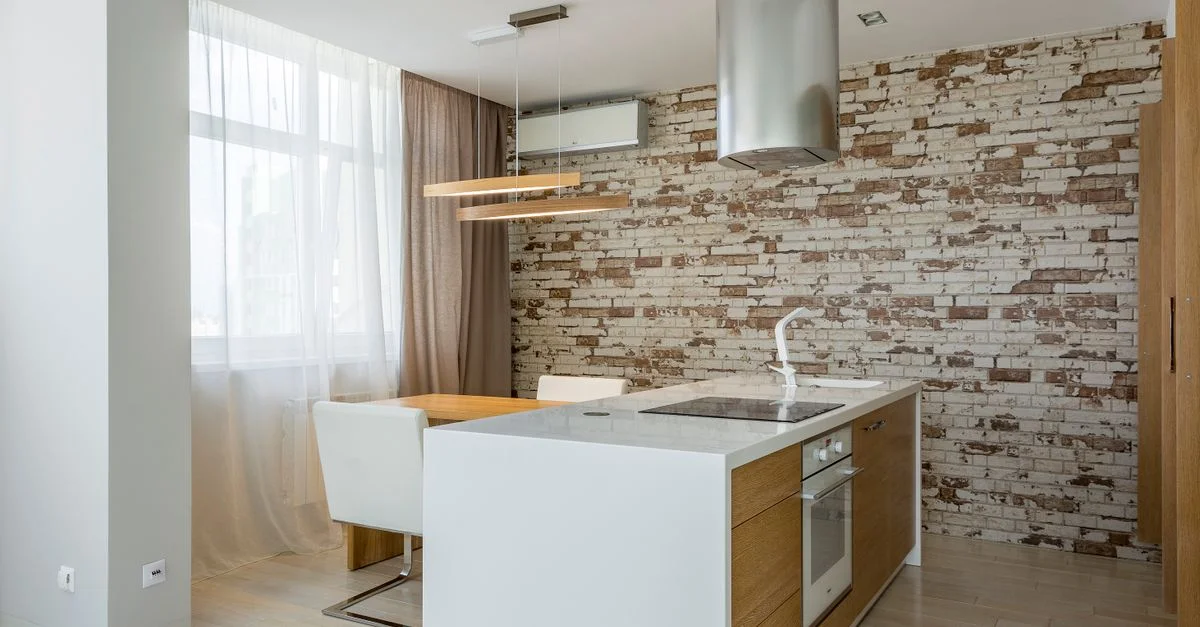 Cuisine contemporaine à plan ouvert avec des éléments de design épurés et un mur en briques rustiques en accent.