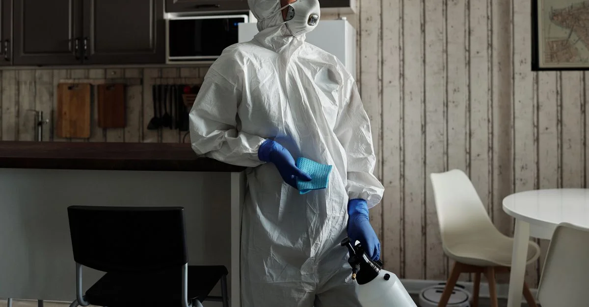 Nettoyeuse en combinaison EPI utilisant un pulvérisateur pour la désinfection à l'intérieur. Concentrez-vous sur la sécurité et l'hygiène.