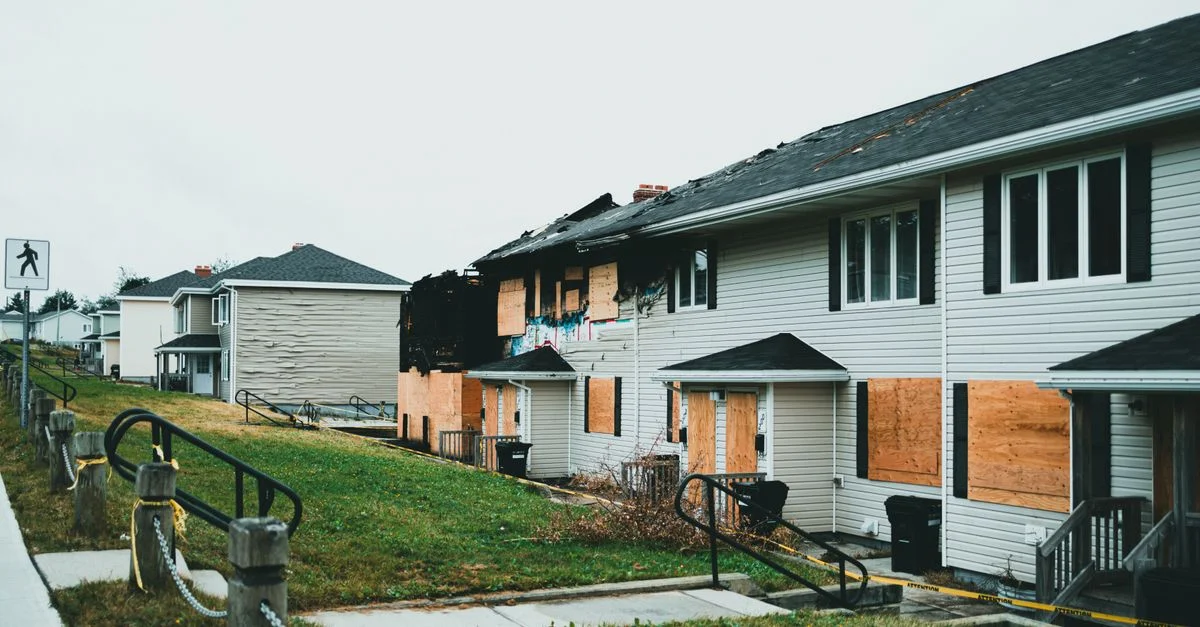 Maisons suburbaines barricadées avec des signes de dommages causés par le feu et de négligence.