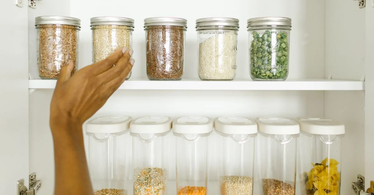 Une étagère de garde-manger bien rangée montrant divers grains stockés dans des conteneurs en verre et en plastique étiquetés, favorisant l'organisation de la cuisine.