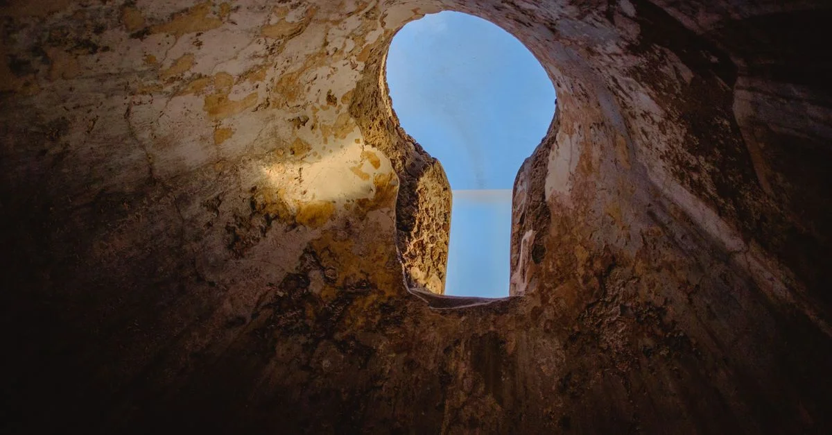 Une vue captivante du ciel bleu à travers une ouverture en forme de trou de serrure dans un mur ancien à Pompéi.