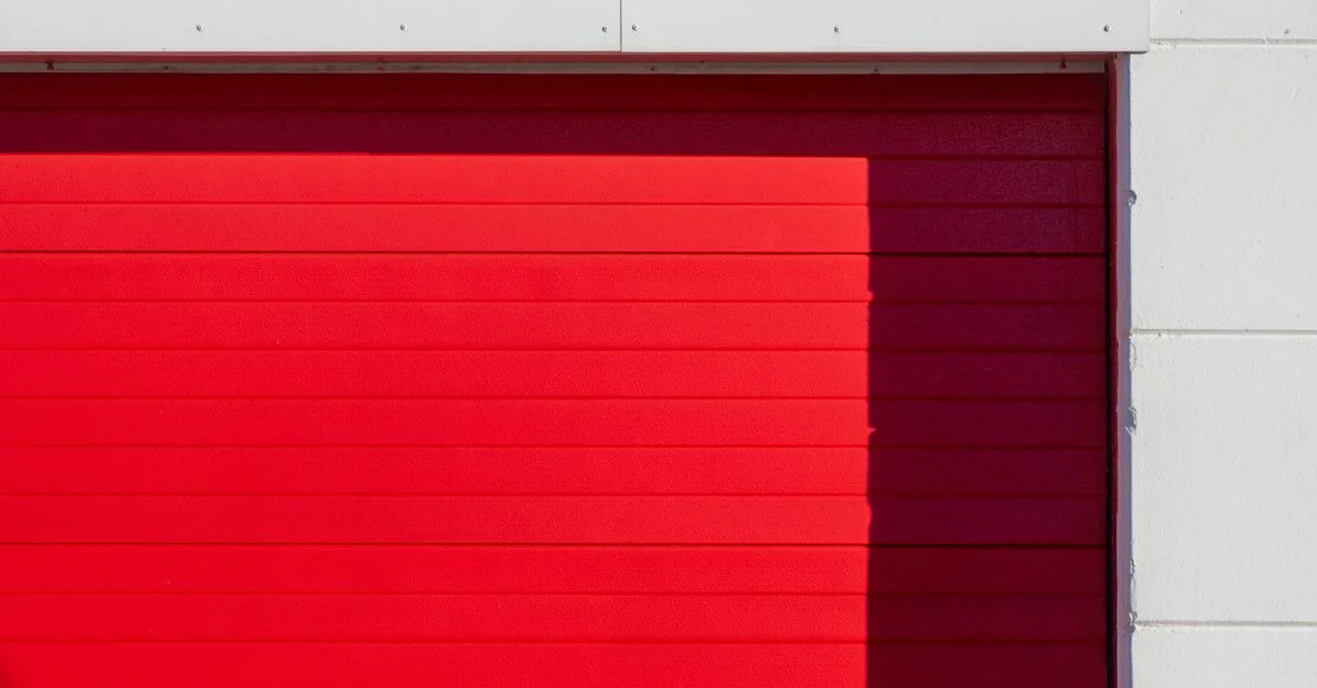 Image minimaliste présentant une porte de garage rouge vif avec une esthétique moderne.