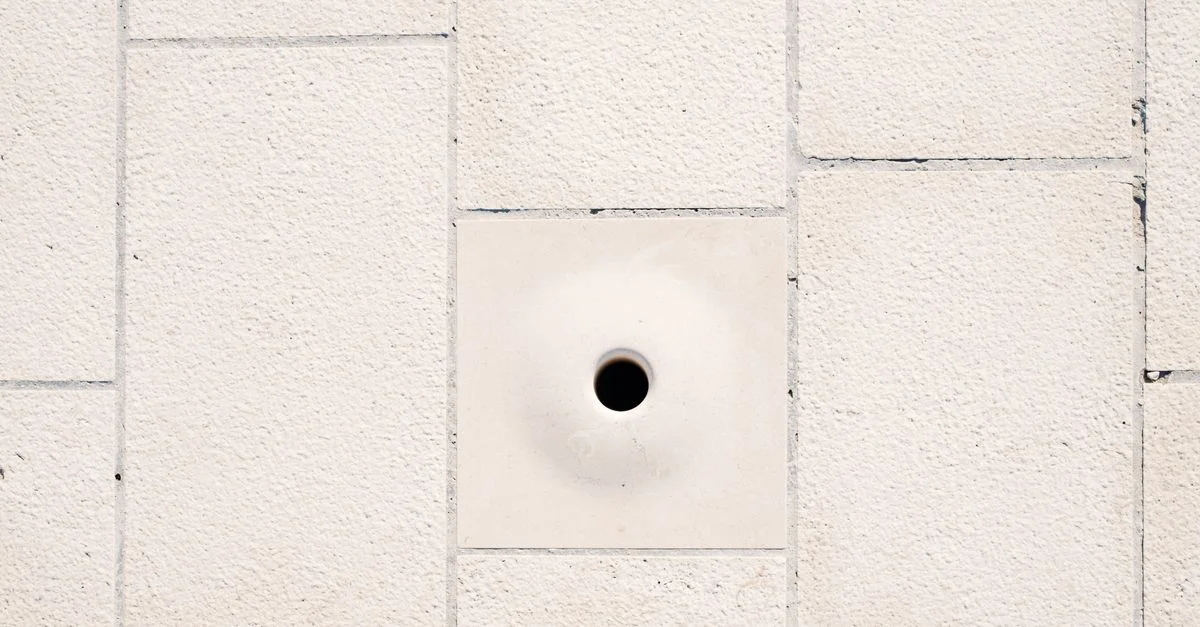 Gros plan sur un mur de briques blanches minimaliste avec un trou circulaire central.