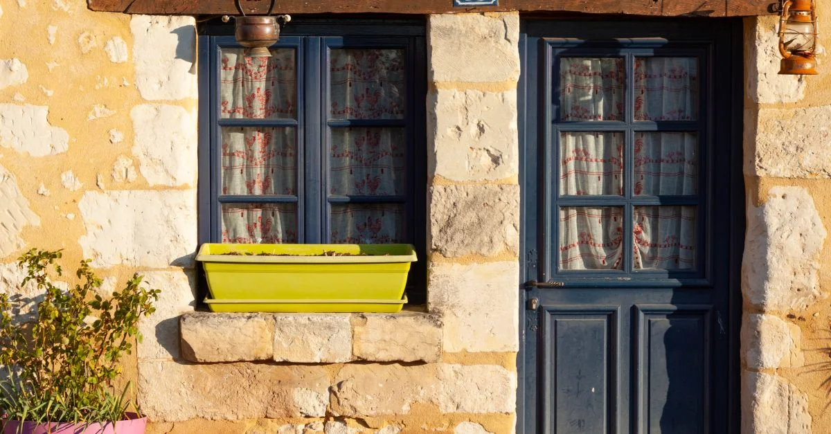 Entrée d'un cottage rustique avec une porte et des fenêtres bleues à Mortagne-au-Perche, France.