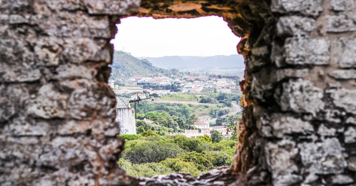 Vue pittoresque d'une ville à travers un trou dans un ancien mur en pierre.