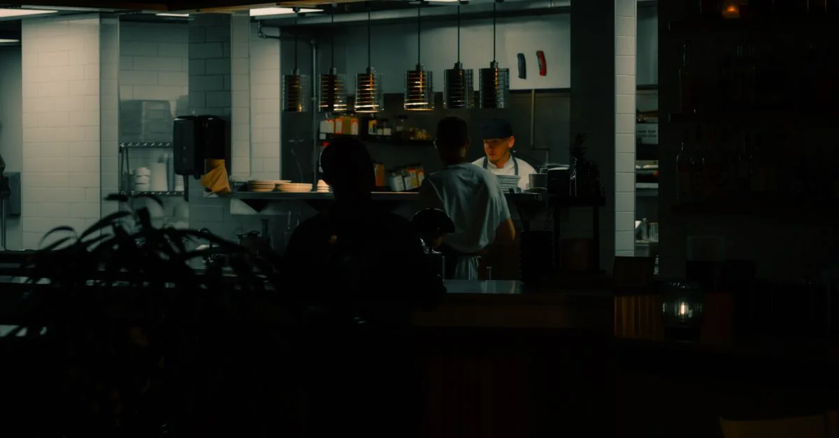 Chefs travaillant dans une cuisine urbaine faiblement éclairée, mettant en avant l'ambiance nocturne.