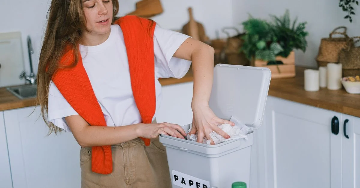 Jeune femme organise du papier recyclable dans sa cuisine pour un mode de vie zéro déchet.