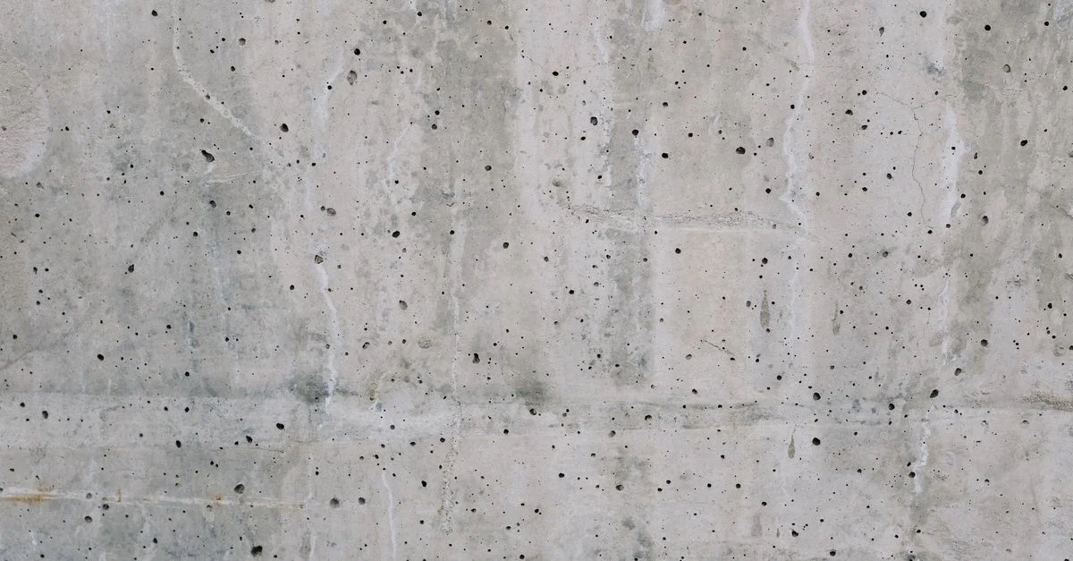 Texture en gros plan détaillée d'un mur en béton avec de petits trous et imperfections.