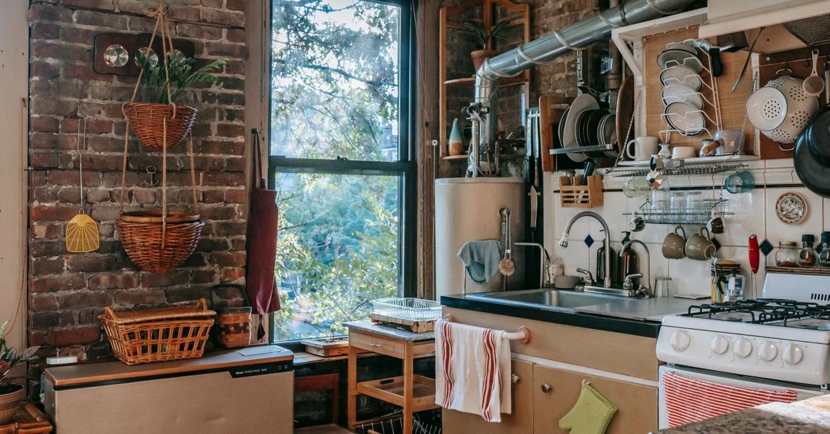 Charmante cuisine rustique avec décor en bois, briques apparentes et appareils avec vue ensoleillée sur la fenêtre.