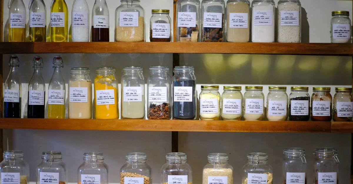 Variété de bocaux remplis de différents ingrédients de cuisine soigneusement disposés sur des étagères en bois.