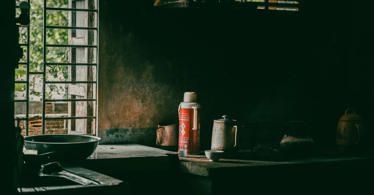 Une cuisine rustique avec des ustensiles vintage et une lumière tamisée, créant une ambiance nostalgique et chaleureuse.